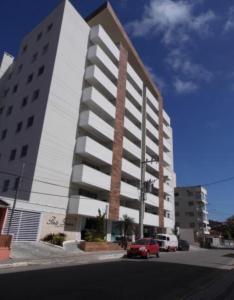 a large white building with a red car in front of it at 100m da Praia Pereque, 3 quartos, Amplo e Aconchegante in Porto Belo