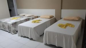two beds with white tables with yellow bows on them at Pousada São Lucas in Salgueiro