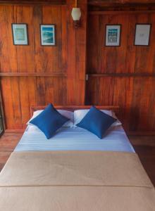 1 cama con 2 almohadas azules en una habitación en Tree Houses by Jungle River, en Ginigathena