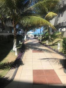 a sidewalk with palm trees and a building and the ocean at Apartamento Ponta Negra in Natal