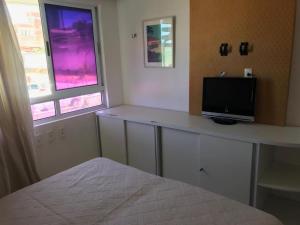 a bedroom with a desk with a television on it at Apartamento Ponta Negra in Natal