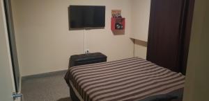 1 dormitorio con 1 cama y TV en la pared en 76 Arruabarrena en Villa Carlos Paz