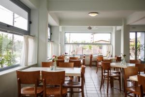 a dining room with tables and chairs and windows at Marialena Hotel in Flogita