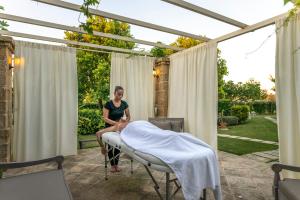 eine Frau, die auf einem Stuhl unter einer Pergola sitzt in der Unterkunft Il Lusso Del Silenzio in Ugento