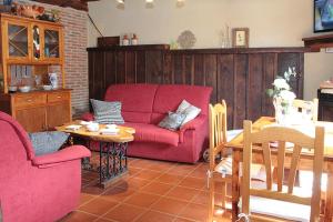 sala de estar con sofá rojo y mesa en Casa de Piedra, en Valderrueda