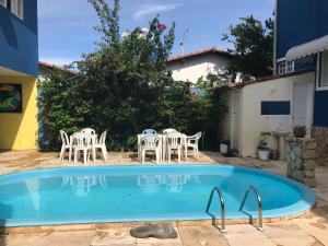 a pool with chairs and a table in a yard at Pousada Pé na Areia in Pipa