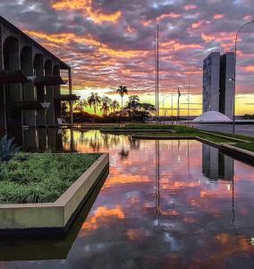 a pool of water with a sunset in a city at APARTAMENTOS NO CENTRO DE BRASILIA. in Brasília