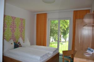 1 dormitorio con cama, escritorio y ventana en Das Grafengut, en Nussdorf am Attersee