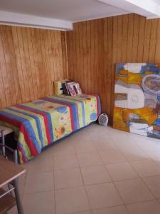 1 dormitorio con 1 cama y una pintura en la pared en Departamentos Buena Vista, en El Quisco