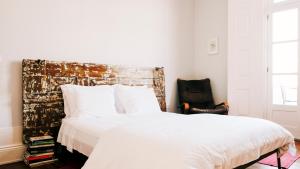 a bedroom with a white bed and a chair at Dona Emília Guest House & Studio Apartments in Viana do Castelo