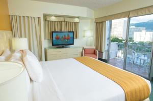 a hotel room with a bed and a television at Coconut Waikiki Hotel in Honolulu