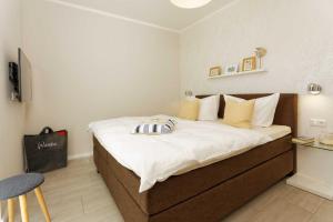 een slaapkamer met een groot bed met witte lakens en gele kussens bij Kapitaensweg 2 Kajuete 03 in Ostseebad Karlshagen