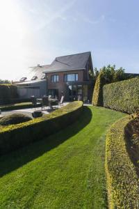 una casa con patio con mesa y césped en Guesthouse De Steenberg 1 x tweepersoonskamer met grote gedeelde badkamer, tuinzicht op de eerste verdieping, en Geel