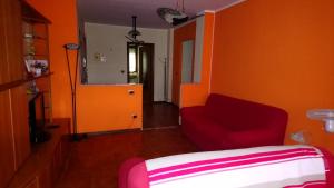 Casa Stellone في Villastellone: غرفة بها أريكة حمراء وجدار برتقالي
