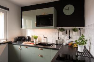 a kitchen with a sink and a clock on the wall at Legnica Apartament 52m2 Delux 1 in Legnica