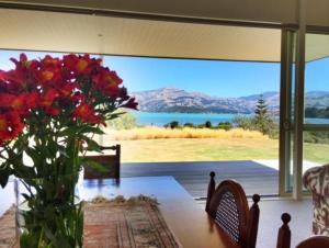a vase of flowers on a table with a view at L'abri Bed and Breakfast in Akaroa