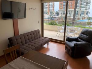 - un salon avec un canapé, une chaise et une télévision dans l'établissement Departamento Viña del Mar Coraceros, à Viña del Mar