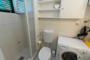 a small bathroom with a toilet and a washing machine at Apartments Ziva in Primošten