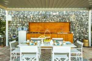 a kitchen with a white table and chairs and a stone wall at Residenza San Luca Praiano in Praiano