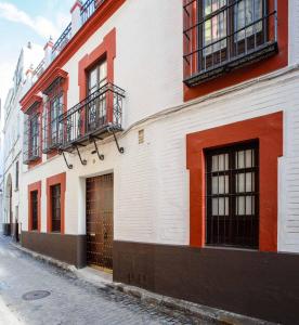 a white and red building with a door on a street at Suites Machado in Seville