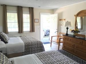 a bedroom with two beds and a dresser with a mirror at Westhampton Seabreeze Motel in Westhampton