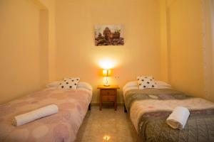 グラナダにあるApartamento Albaycin Granadaのベッド2台、ランプ1台、テーブルが備わる客室です。