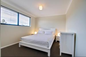a white bedroom with a bed and a window at A Little Luxury in Town in Dunsborough