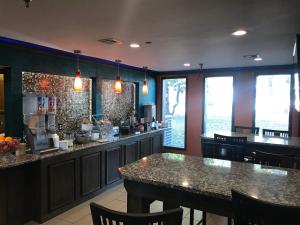 un restaurante con un bar con mesas y sillas en Super 8 by Wyndham Fayetteville, en Fayetteville