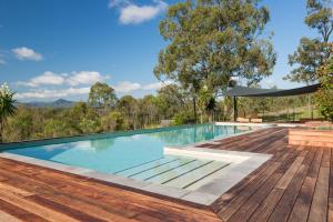 an outdoor swimming pool with a wooden deck at Spicers Hidden Vale in Grandchester