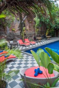 a resort pool with red chairs and a checkered floor at Abian Srama Hotel and Spa in Sanur