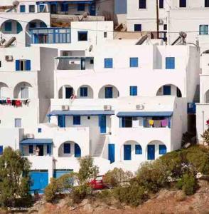 a large white building with blue doors and windows at Panorama Rooms in Anafi