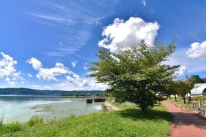 uma árvore ao lado de um corpo de água com um céu em 天然個室温泉 HOTEL Lafontaine 諏訪 em Suwa