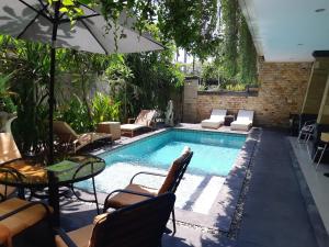 a swimming pool with chairs and a table and an umbrella at Lotus Tirta Seminyak in Seminyak