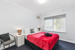a bedroom with a red bed with a chair and a window at Wattle Grove Villa in Maryborough