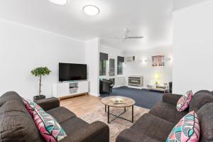 a living room with two couches and a tv at Wattle Grove Villa in Maryborough