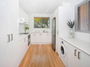 a kitchen with white cabinets and a wooden floor at Waves Appartment in Kiama