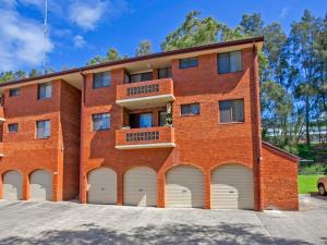 a red brick building with four white garage doors at Waves Appartment in Kiama