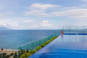 a person standing on the edge of a swimming pool overlooking the ocean at Nagar Hotel Nha Trang in Nha Trang