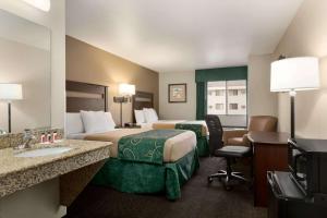 a hotel room with two beds and a bathroom at Baymont by Wyndham Glendive in Glendive