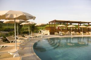 una piscina con tumbonas y sombrillas en Le Fiabe Hotel Resort, en Numana