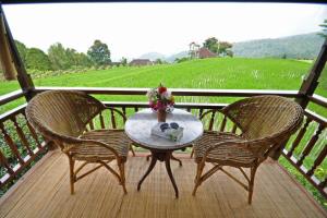 een tafel en twee stoelen op een veranda met uitzicht bij Puri Lumbung Cottages Restaurant & Spa Munduk in Munduk