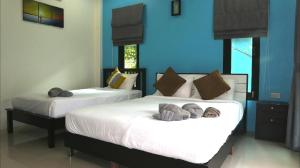 two beds in a room with blue walls at Lanta Memory Resort - SHA Plus in Ko Lanta