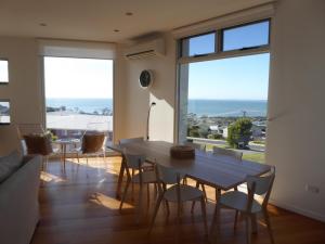 a dining room with a table and chairs and windows at Bridport Horizon Views in Bridport