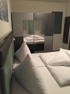 a bed with white pillows in a room with a mirror at Apart Alpenblick in Pfunds