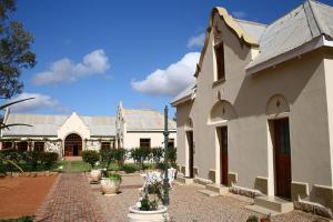 a large white building with a brick courtyard at Rietfontein Ostrich Palace in Vleirivier