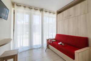 カップ・ダグドにあるAzureva Cap d'Agdeの大きな窓付きの客室で、赤いソファが備わります。