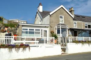 a white fence in front of a house at Sea View Guest House in Benllech