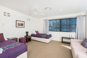 a bedroom with two beds and a couch and a window at Byron Bay Accom Unit 2 8 Lawson Street, Byron Bay - Absolute Solace in Byron Bay