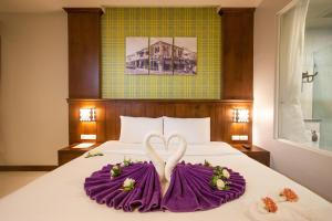 ein Bett mit zwei Schwänen aus lila Handtüchern in der Unterkunft Supicha Pool Access Hotel - SHA Plus in Phuket