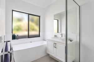 Baño blanco con lavabo y espejo en Diamond Bay Beach House: brand new, en Sorrento